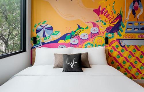 吉隆坡lyf Chinatown Kuala Lumpur的一间卧室设有两张白色的床和色彩缤纷的墙壁