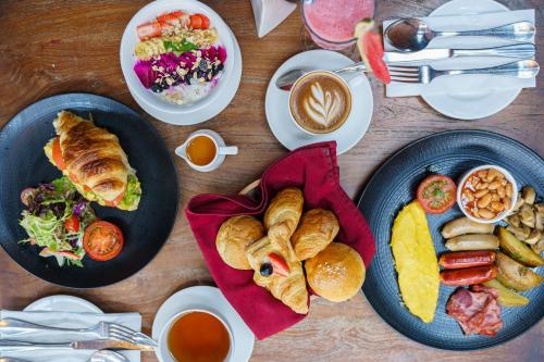 库塔Fairfield by Marriott Bali South Kuta的木桌,带盘子的食物和咖啡杯