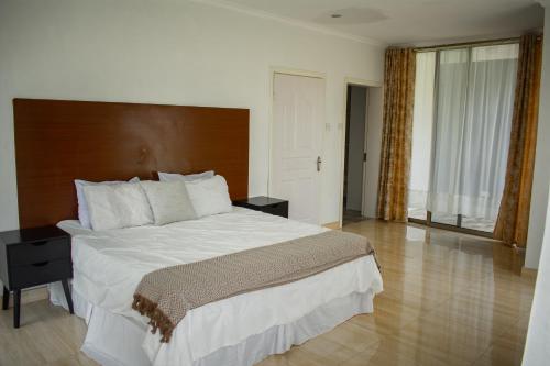 利隆圭Divine Heights Apartments Lilongwe Area 43的一间卧室配有一张大床和木制床头板