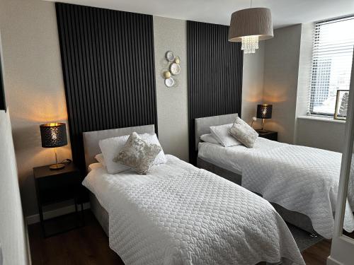 利物浦Stunning two bed city Center apartment的一间卧室配有两张带白色床单的床