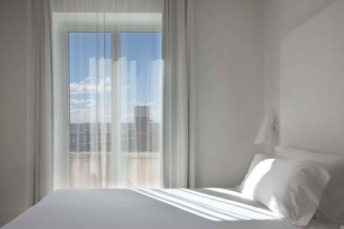 马德里马德里阿托查NH酒店的一间卧室设有一张床和一个美景窗户。
