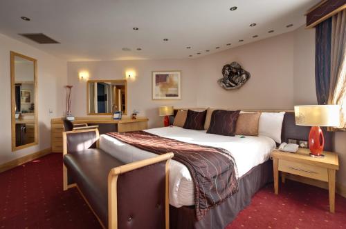 诺斯利The Suites Hotel & Spa Knowsley - Liverpool by Compass Hospitality的酒店客房设有一张大床和一张沙发。