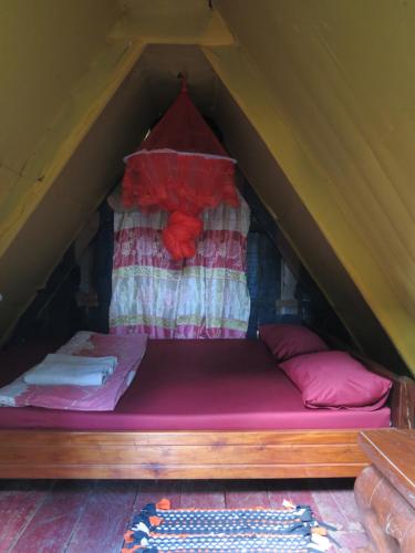 邦隆Ratanakiri Homestay & Jungle Trek的一张位于帐篷内的床位,配有粉色床单和枕头