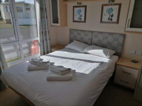 罗切斯特Kent Coast Holiday Park的卧室配有带毛巾的大型白色床