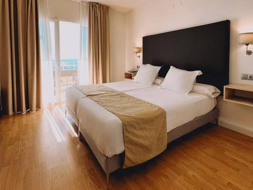 林孔-德拉维多利亚Fay Victoria Beach的一间卧室设有一张大床和大窗户