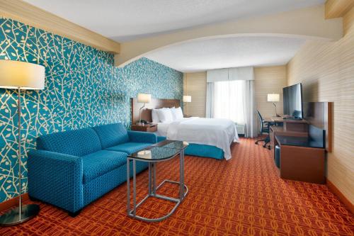 米西索加水牛城机场万豪费尔菲尔德客栈的酒店客房,配有床和蓝色的沙发