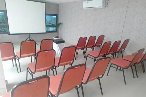 KedatonTera Guest House的一个带红色椅子和屏幕的讲座室