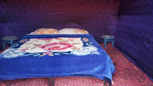 AdrouineGambe Camp的一张带蓝色棉被的床和两张桌子