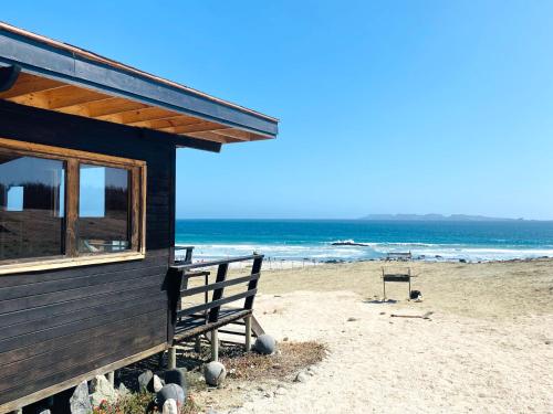蓬塔乔罗斯Punta de Choros Lodge的海滩上的房子,带长凳和大海