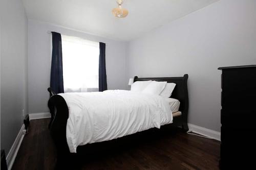 温尼伯Cozy Airport 2-bed的一间卧室配有一张带白色床单的床和一扇窗户。