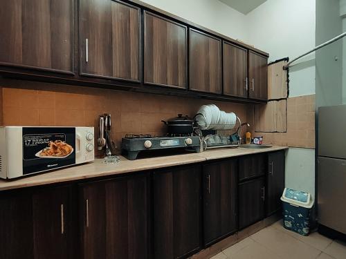 伊斯兰堡The Choice of families APARTMENTS的厨房配有木制橱柜和台面上的微波炉
