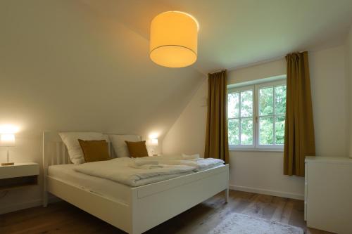 不来梅·弗格萨克Exklusives Reetdachhaus in der Bremer Schweiz的卧室配有白色的床和窗户。