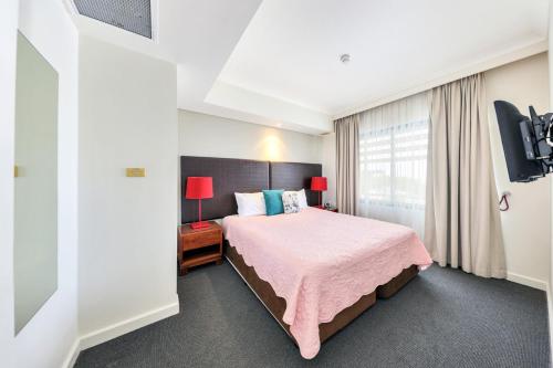 达尔文Resort Style City View King Bed Pool Balcony的卧室配有粉红色的床和窗户。