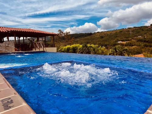 圣希尔Hotel Campestre Palmas del Zamorano的一个带凉亭的大型蓝色海水游泳池