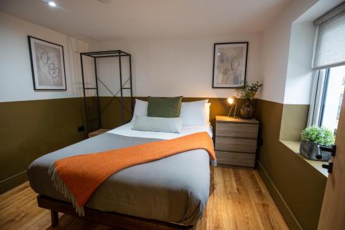 兰鲁斯特RWST Holiday Lodges的一间卧室配有一张带橙色毯子的床