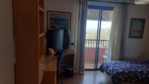 特格斯特安娜加托旅馆的一间带电视和床的卧室以及一个阳台