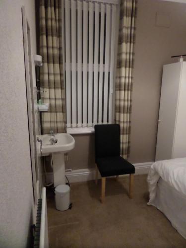 布莱克浦Nathans Guest House的一间带水槽的浴室和窗户旁的椅子