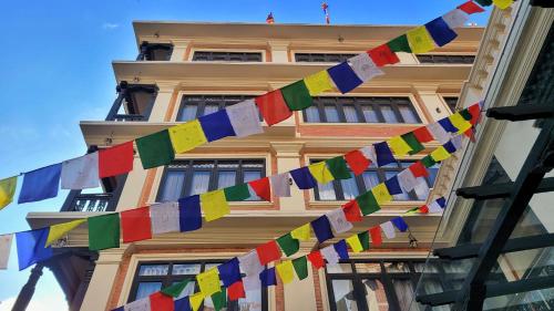 加德满都SWARGA HERITAGE HOTEL - A TRADITIONAL STAY的一座建筑,前面有五颜六色的祈祷旗帜