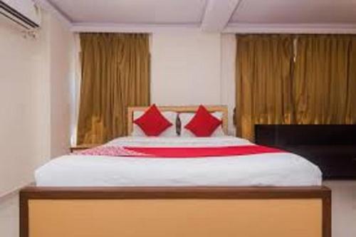 孟买HOTEL ORBITINN MALAD的一间卧室配有一张带红色枕头的大床