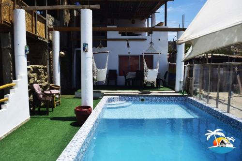 卡诺阿斯德蓬萨尔Hospedaje Casa Mercedes Beach的一个带椅子的庭院和房子的游泳池