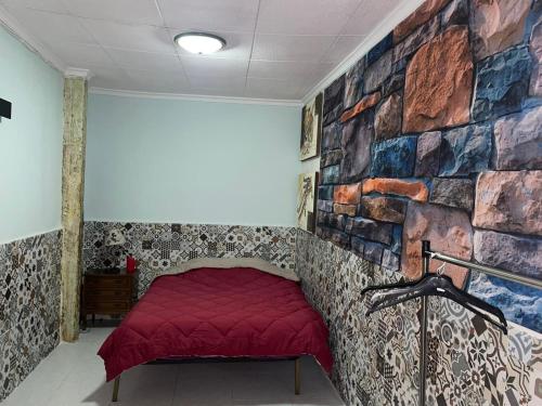 卡塔赫纳Amplia habitación céntrica的一间石墙边的红色床间