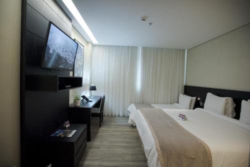 贝洛奥里藏特Tryp by Wyndham Belo Horizonte Savassi的酒店客房设有两张床和一台平面电视。