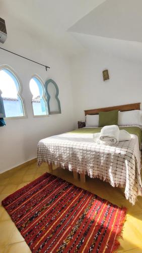 舍夫沙万Honey Suckle的一间卧室配有一张带地毯的床和两个窗户