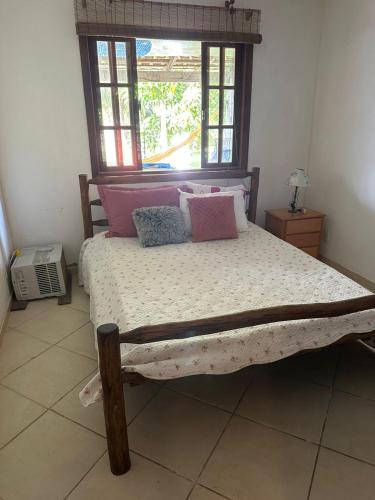 布希奥斯Casa em Búzios的卧室配有带枕头的床铺和窗户。