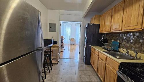 纽约Sylish 1 Bedroom Apartment in NYC!的厨房配有不锈钢冰箱和木制橱柜