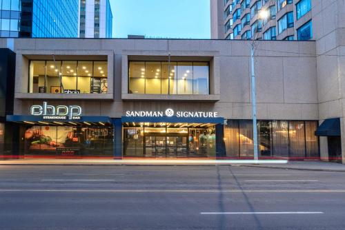 埃德蒙顿Sandman Signature Edmonton Downtown Hotel的城市街道上建筑物前面的商店