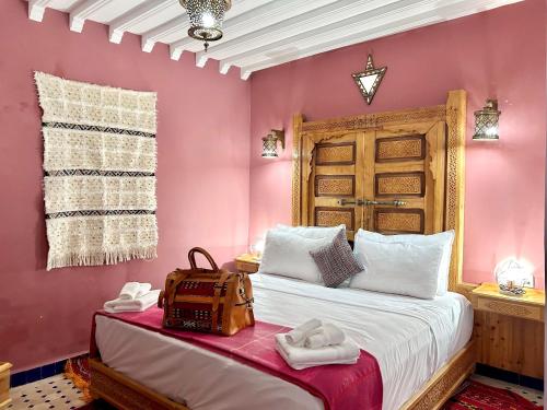 非斯Riad Noor Medina的卧室设有粉红色的墙壁和一张带袋子的床