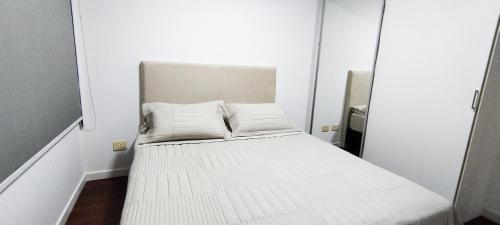 亚松森Hermoso departamento en Skytower的一张小白色床,位于带镜子的房间里