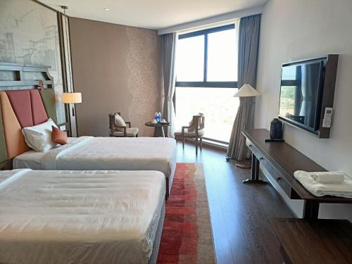 Ấp Thiẹn ÁiLuxury APEC MANDALA MŨI NÉ SG HAPPY HOUSE的酒店客房设有两张床和电视。