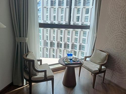 Ấp Thiẹn ÁiLuxury APEC MANDALA MŨI NÉ SG HAPPY HOUSE的客房设有一张桌子、两把椅子和一个大窗户