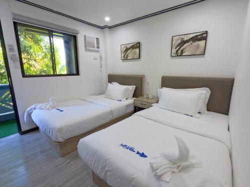 科隆Lucky Tito Coron Dive Resort的酒店客房设有两张床和窗户。
