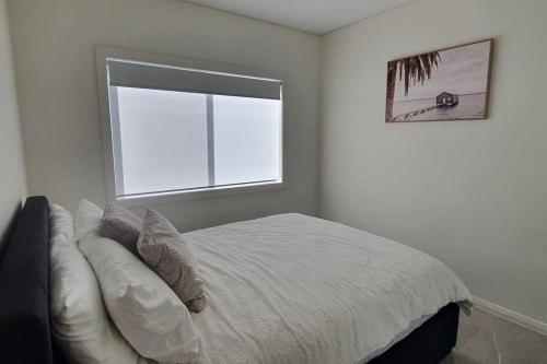 Panania1/84的白色卧室设有一张带窗户的床