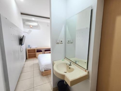PuunggolakaUrbanview Hotel B Liv Kendari的一间带水槽和镜子的浴室以及一张床