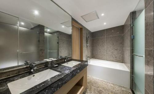 西归浦市济州岛城山贝斯特酒店的浴室配有两个盥洗盆和浴缸。