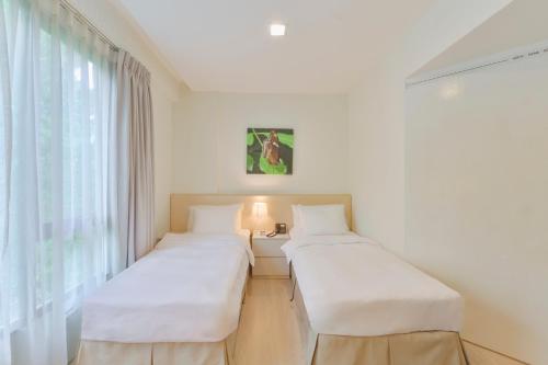 新加坡Changi Cove的白色客房的两张床,设有窗户