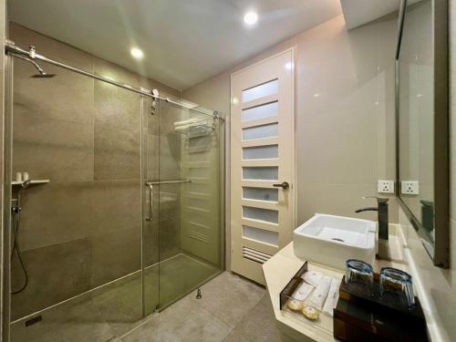 山打根利文斯顿酒店的一间带玻璃淋浴和水槽的浴室