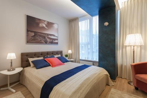 维尔纽斯罗柯洛思公寓式酒店的一间卧室配有一张带蓝色和红色枕头的大床