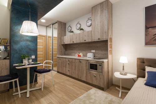 维尔纽斯罗柯洛思公寓式酒店的厨房配有木制橱柜和桌椅