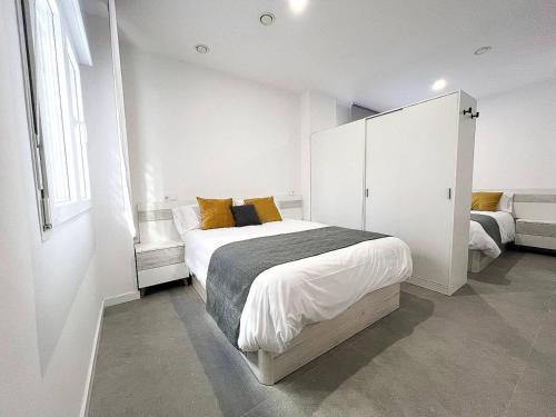 马拉加Studio Alborán的白色卧室配有一张带黄色枕头的大床