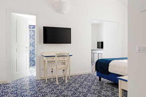 伊斯基亚大拉斐尔酒店 的一间卧室配有一张床、一张书桌和一台电视。