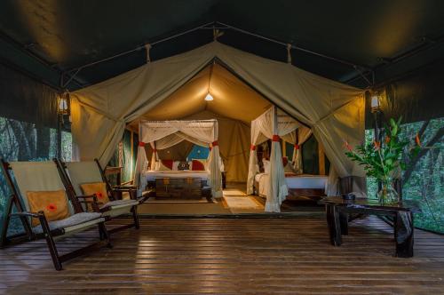 马赛马拉Soroi Mara Bush Camp的帐篷里设有一张床和一个女人