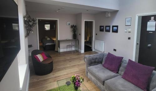 哈罗盖特Harrogate Lifestyle Luxury Serviced ApartHotel的客厅配有沙发和紫色枕头