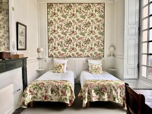 勒芒Demeure Jousset des Berries的一间设有两张床和花卉挂毯的房间