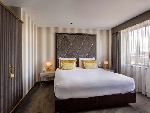惠灵顿惠灵顿索菲特酒店的卧室配有一张带黄色枕头的大型白色床。