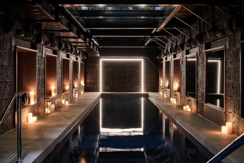 墨尔本Adina Apartment Hotel Melbourne, Pentridge的室内的游泳池,有蜡烛和灯光
