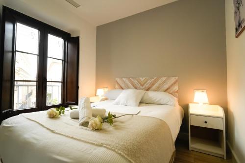 赫雷斯-德拉弗龙特拉Apartamentos Consistorio Live的卧室配有带鲜花的白色床